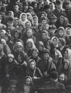A close-up of the standing-room only crowd of immigrants on the deck of a steamship bound for the United States. 