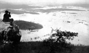 A man sits in an outcropping on Lookout Mountain in 1867, while the town of Chattanooga, shown below him, is completely underwater. 