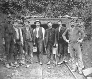 A group of 7 miners standing in front of a coal mine in Anderson County