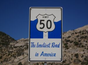 A highway sign in Nevada with the Highway 50 marker on it, and beneath it the words "The Loneliest Road in America."